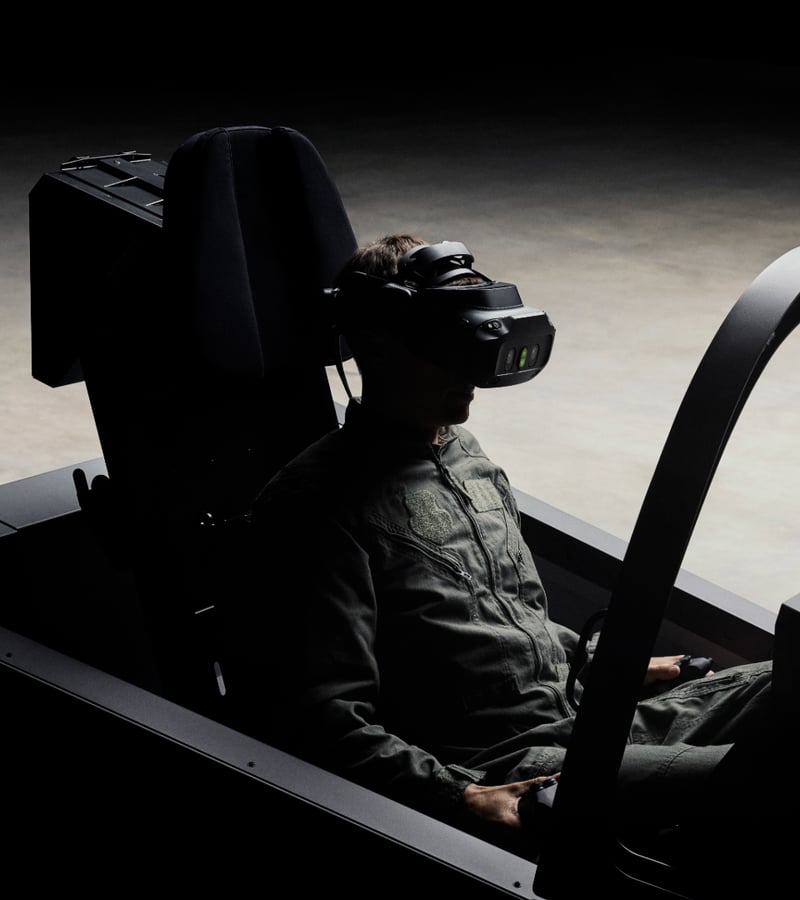A person sitting in a flight simulator, wearing a VR headset